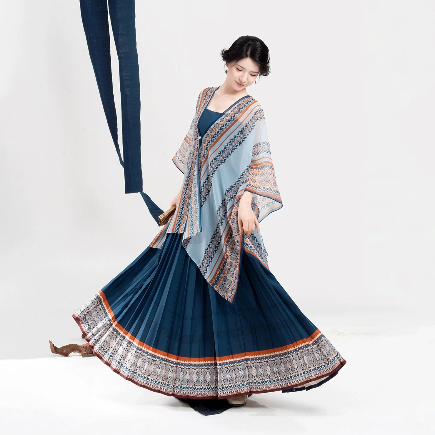 Side view of a woman twirling the neatly pleated skirt of a Dong-inspired modern Hanfu dress with matching light blue patterned shawl