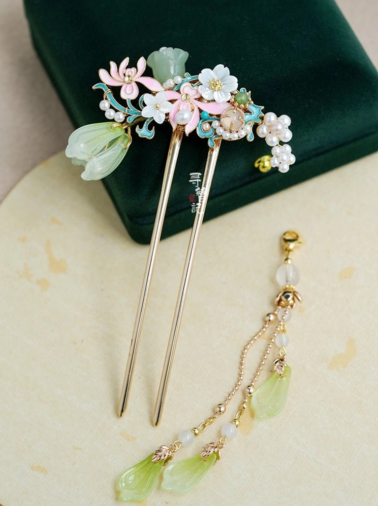 Double pronged Chinese floral hairpin with detachable tassel, pink and white flower enamel details, pearl accents, green jade look charms, gold tone hardware, and green glass droplet pendants