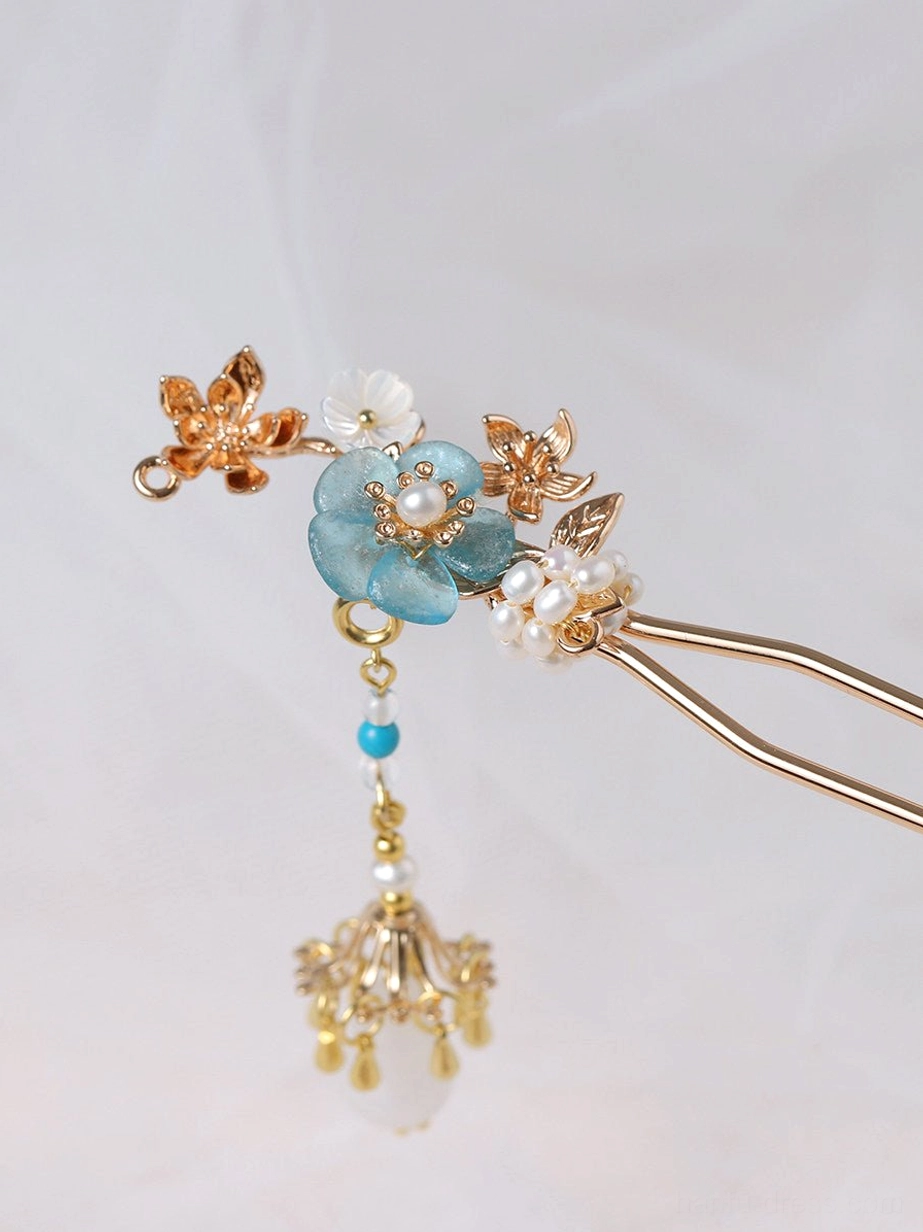 Flat lay of double-pronged turquoise blossom Chinese hair stick showing metal prongs pearl flower cluster and turquoise beaded tassel
