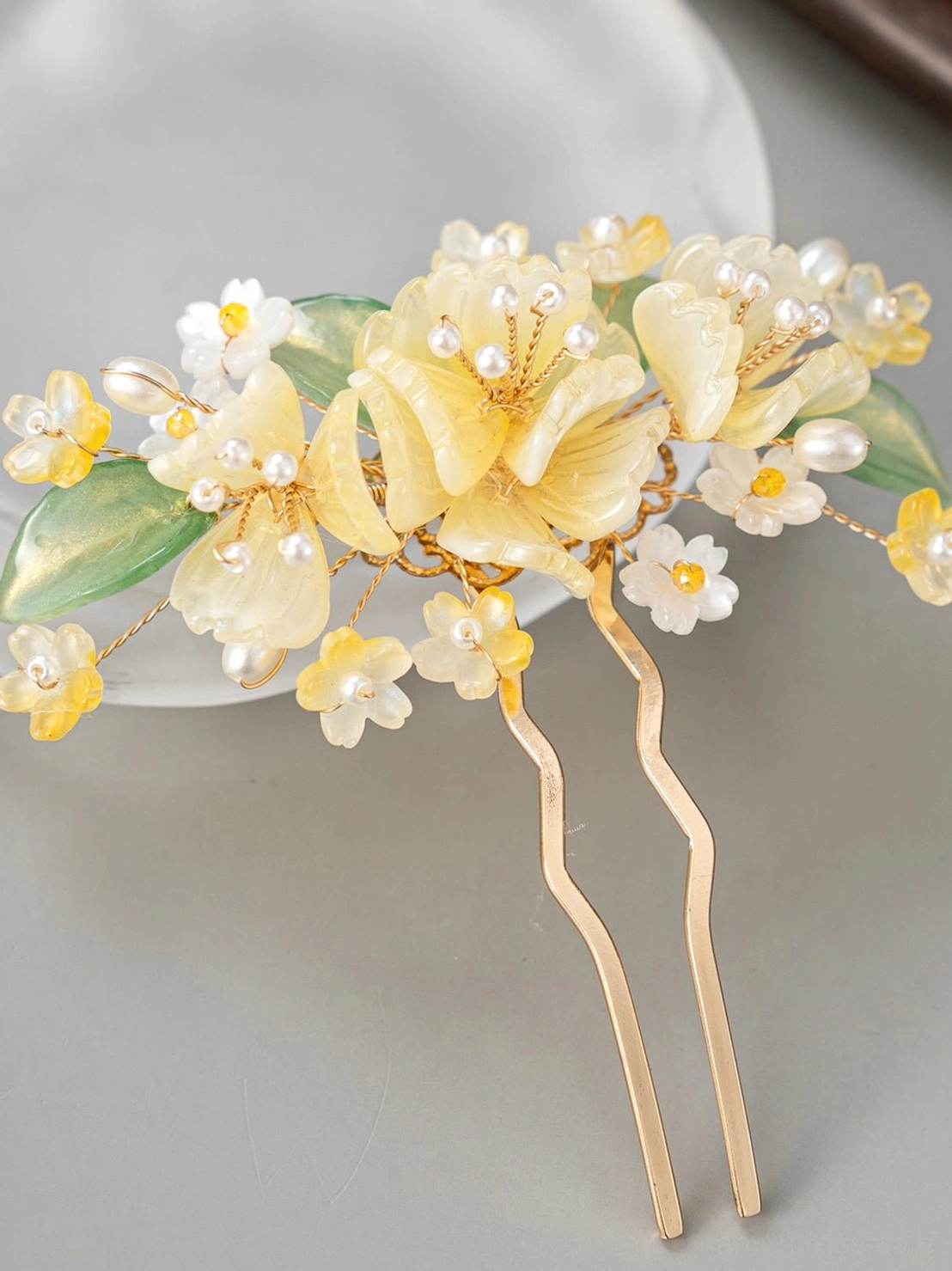 Double-pronged yellow floral Hanfu hairpin with delicate flowers faux pearl accents green leaves and gold-tone metal prongs