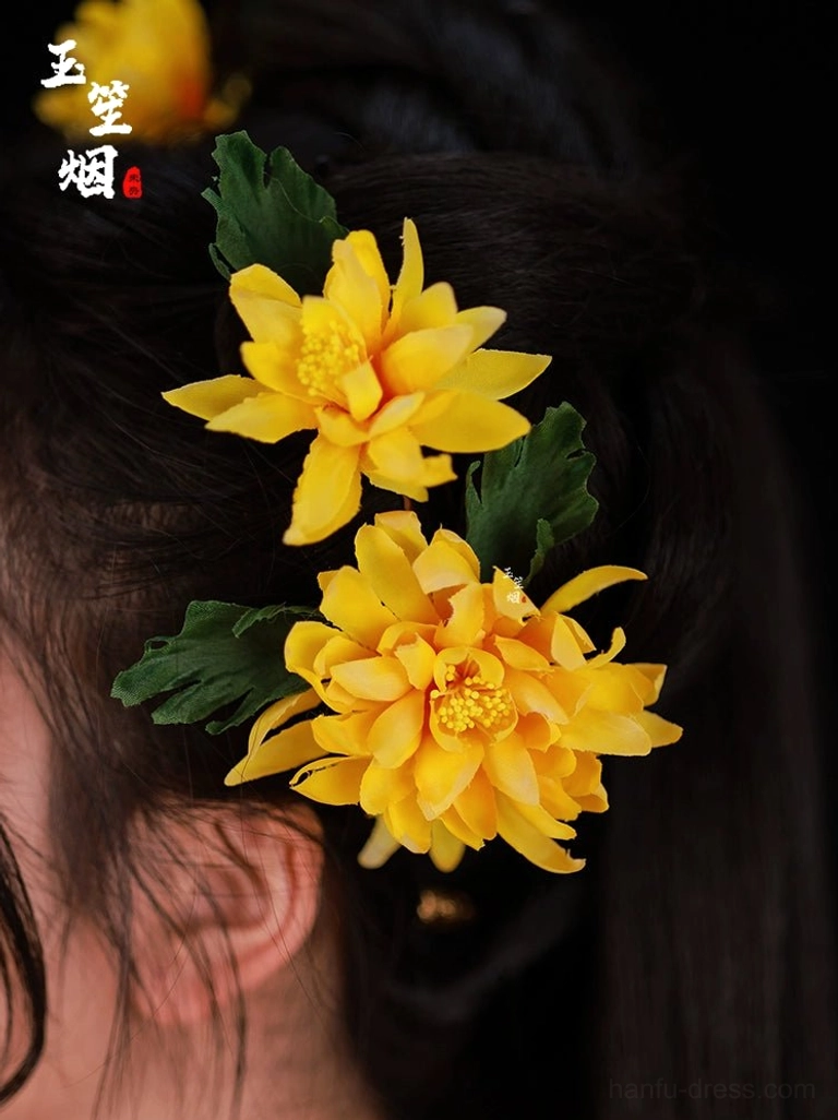 Close-up side view of double yellow chrysanthemum hair pins with green leaves styled in a traditional Chinese Hanfu updo