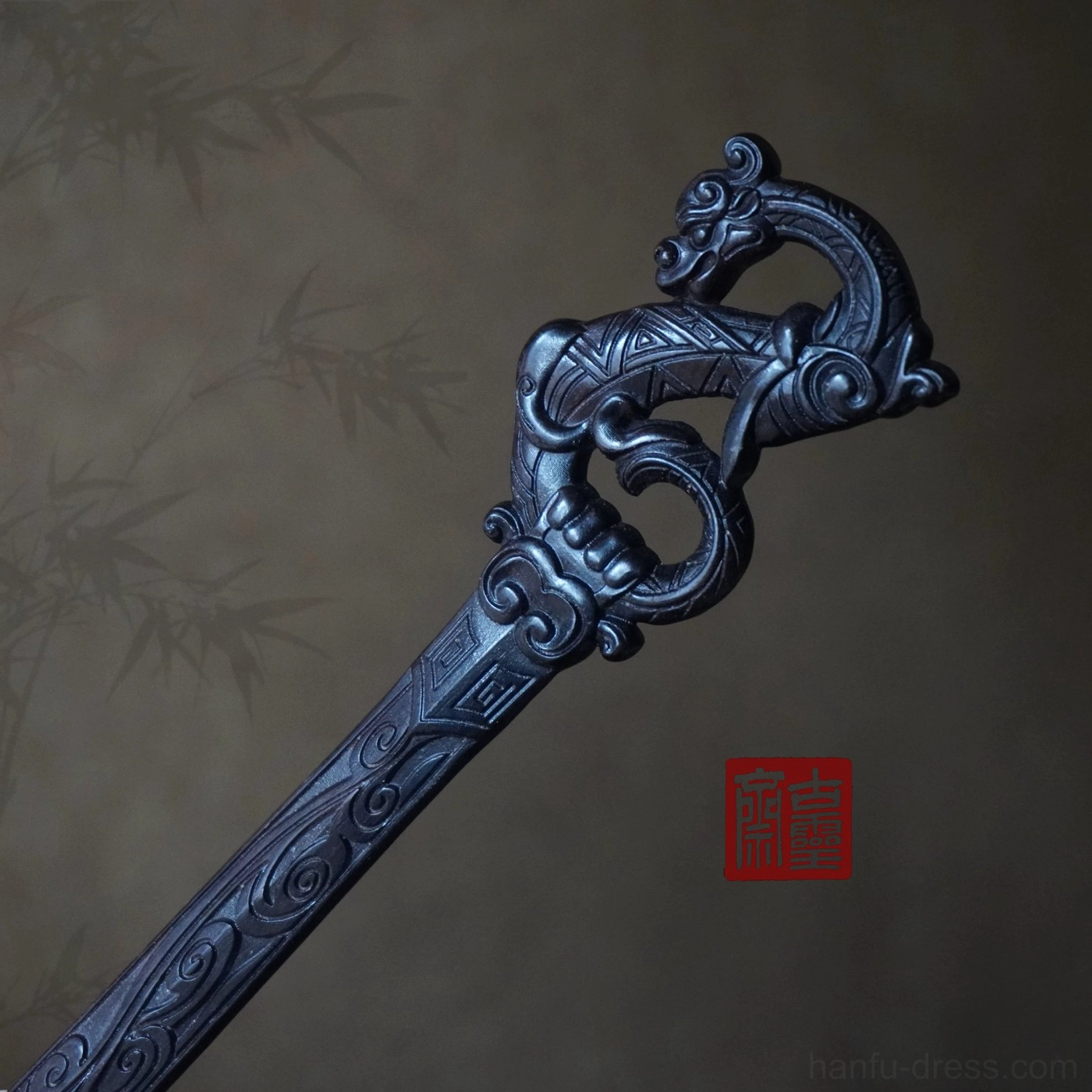 Traditional dragon Chinese hair stick in dark carved finish shown at an angled view on a bamboo shadow background