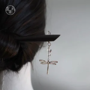 Dragonfly Chinese hair stick worn in a coiled dark hairstyle, featuring a matte black wooden hairpin, silver dragonfly pendant, and clear crystal-style beads for Hanfu styling