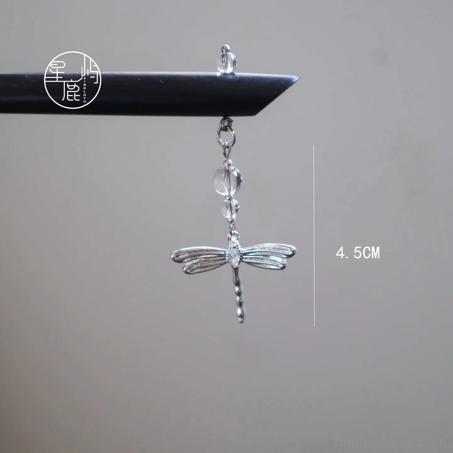 Dragonfly hair stick studio detail showing the black ebony-style wooden pin and approximately 4.5 centimeter silver dragonfly hanging ornament with crystal-style accents