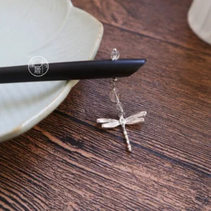 Dragonfly Hanfu hair accessory displayed on a dark wooden table, showing the black wood hair stick, silver-toned dragonfly charm, and delicate beaded hanging chain