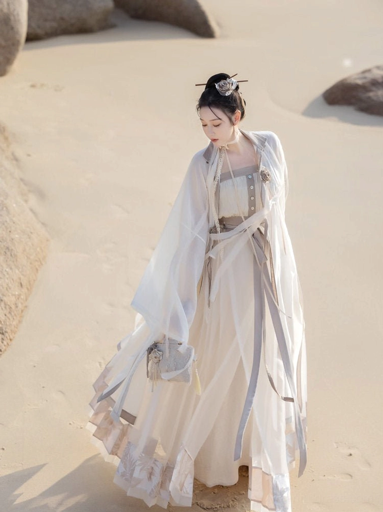 Dream of Mountains Tencel Hanfu outfit shown in a full body three quarter walking view, with a lightweight cream robe, wide sheer sleeves, grey waist sashes, and flowing mamian skirt
