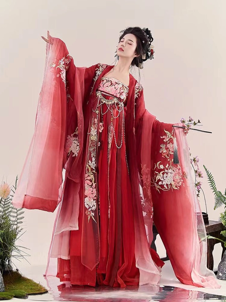 Rear three-quarter view of red Tang Dynasty style Heziqun Hanfu with embroidered wide sleeves and flowing skirt