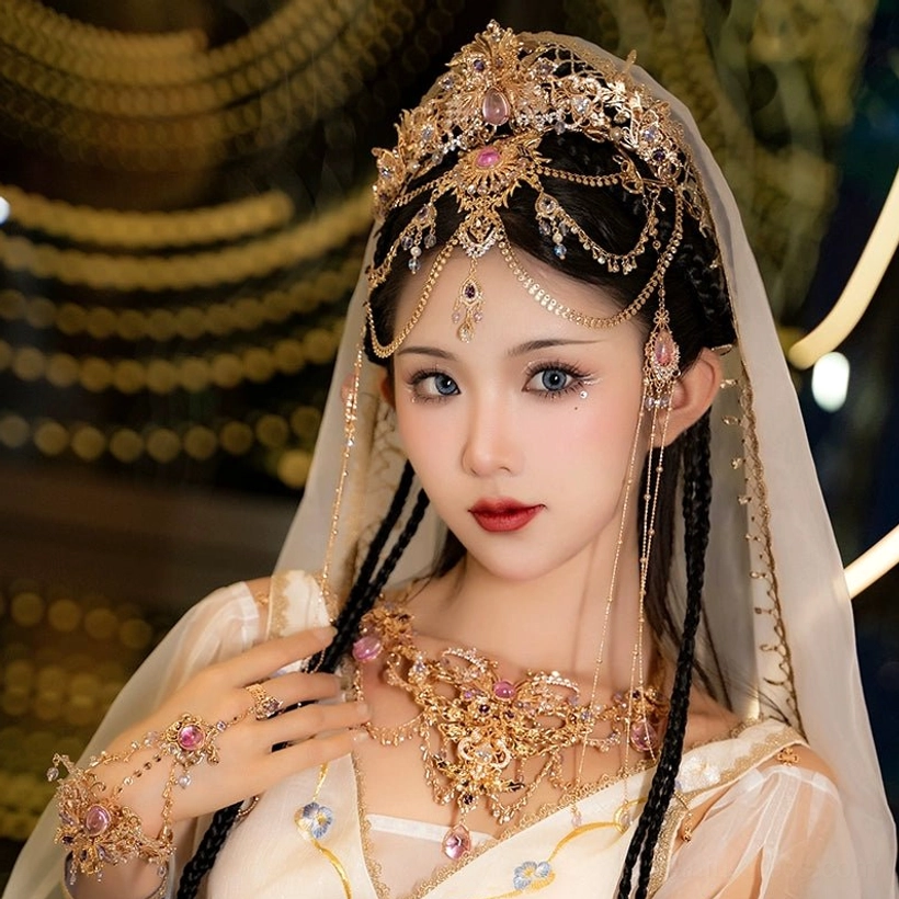 Dunhuang-inspired Hanfu hair accessories set with gold-tone crown, pink-purple crystal accents, layered chain tassels, and coordinated traditional Chinese jewelry worn with a white flowing Hanfu outfit