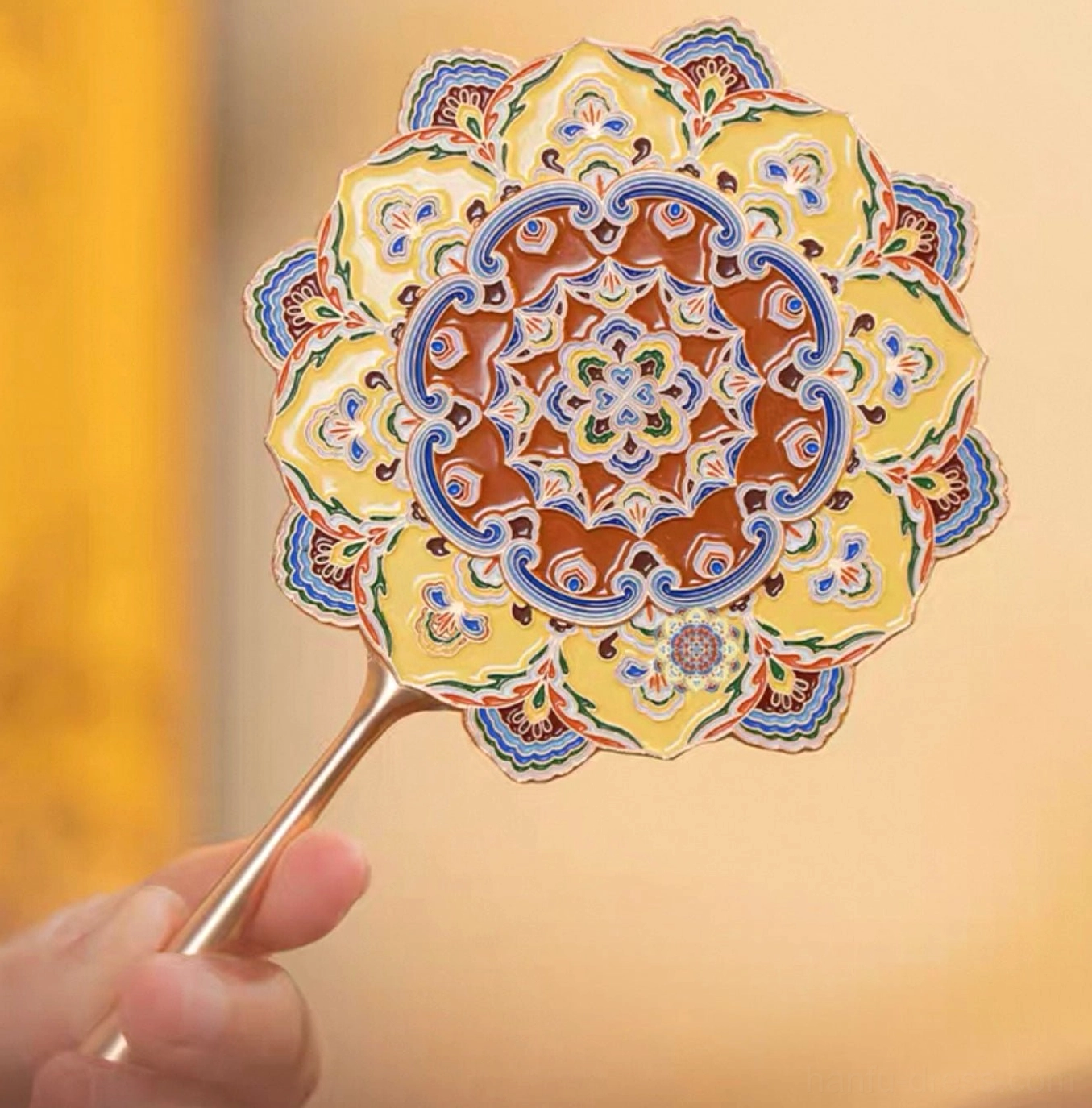 Close-up front view of a Dunhuang lotus caisson Chinese hand mirror with layered floral shape, colorful enamel-style Mogao Cave patterns, turquoise blue yellow and terracotta details, and a polished gold-tone handle