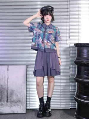 Full body view of a woman wearing a Dunhuang mythical creature print short sleeve modern Hanfu shirt styled with dark shorts, black socks, platform loafers, and a newsboy cap