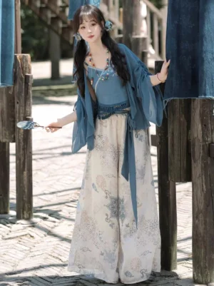 Dusty blue modern Hanfu three-piece outfit with chiffon cardigan, cropped camisole and printed wide-leg pants in an ancient town street