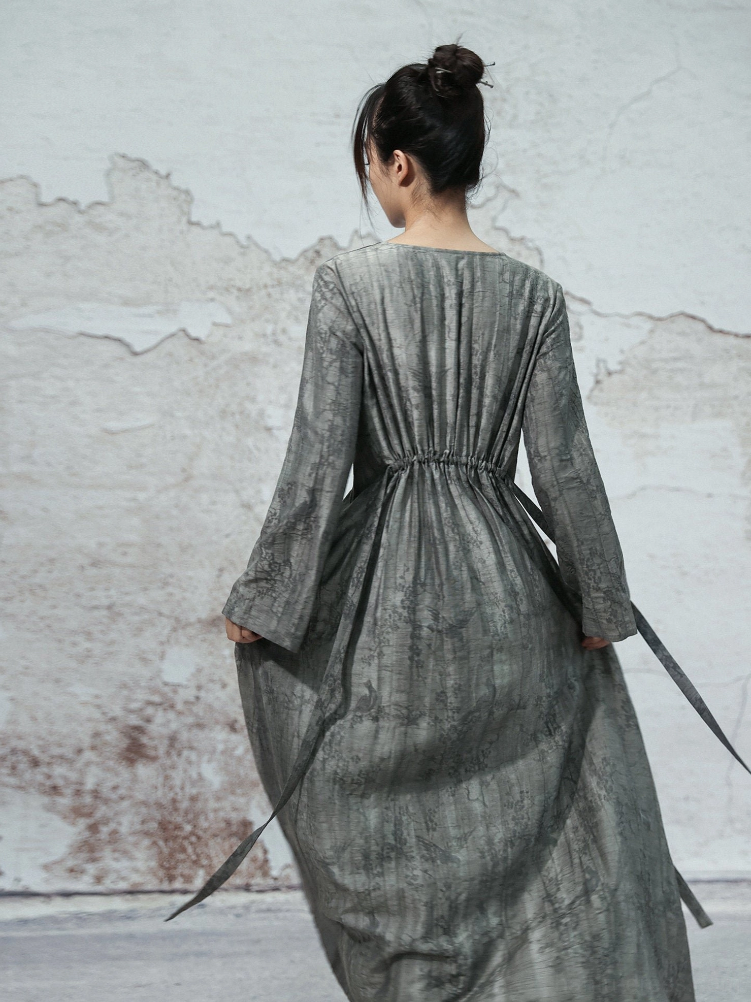 Back view of dusty grey modern Hanfu maxi dress showing gathered back waist, long adjustable sash, relaxed sleeves and flowing A-line silhouette