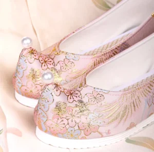 Dusty pink traditional Chinese Hanfu shoes with upturned toes, gold crane and blossom embroidery, pearl toe decoration, and white rubber soles