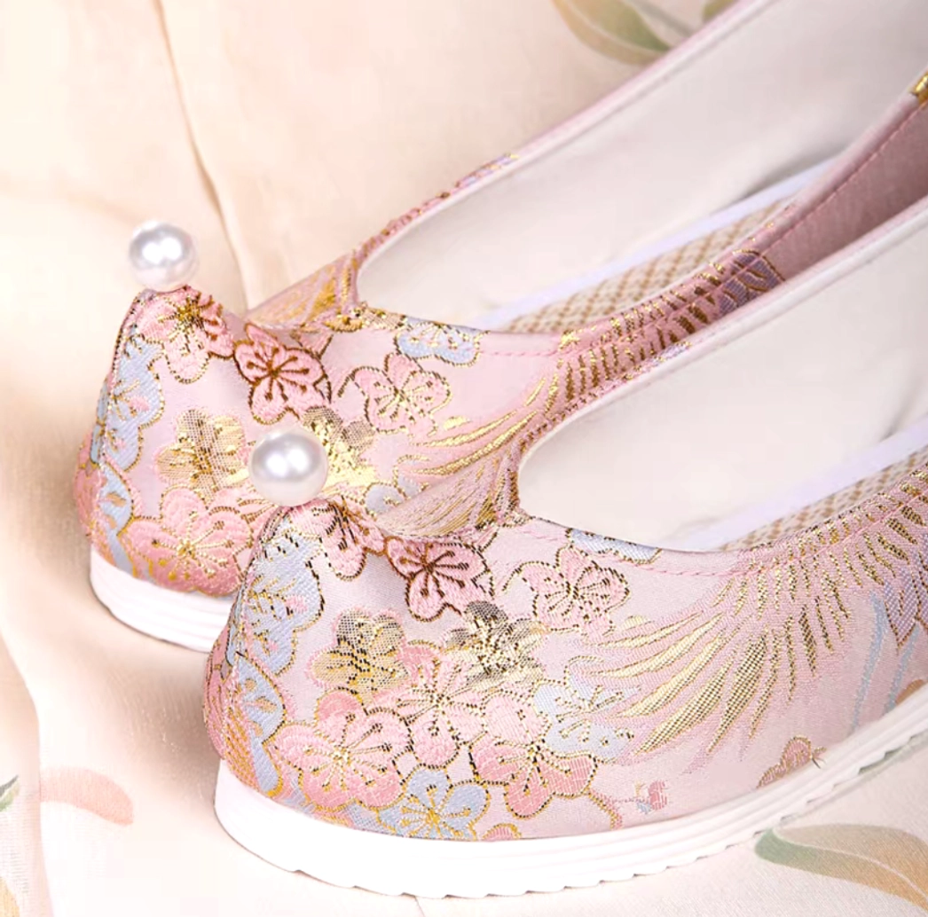 Dusty pink traditional Chinese Hanfu shoes with upturned toes, gold crane and blossom embroidery, pearl toe decoration, and white rubber soles