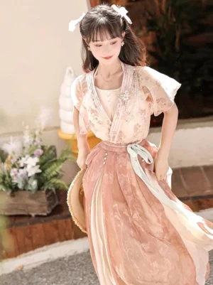 Front three quarter view of a dusty pink floral modern Wei-Jin style Hanfu set with chiffon coat ruffled sleeves cross V-neck camisole and flowing high waisted skirt