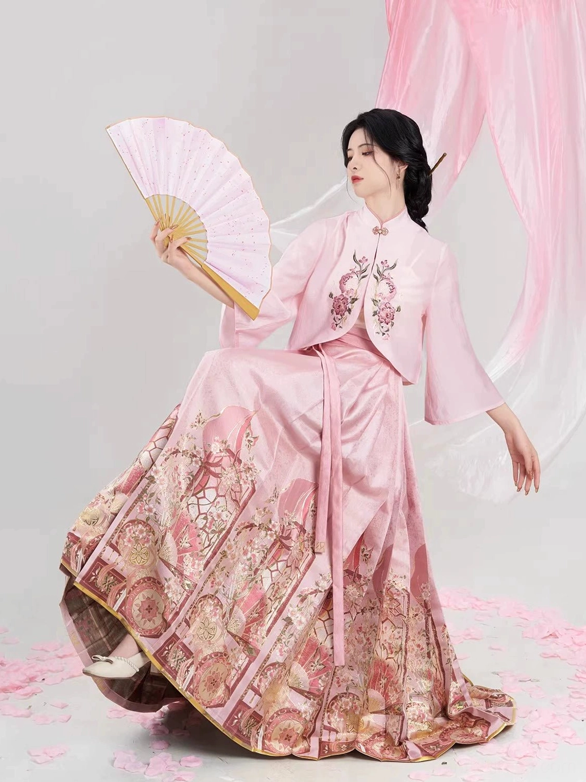 Low-angle view of a dusty pink hanfu outfit with wide flared sleeves, pleated mamian skirt, and oriental garden print details