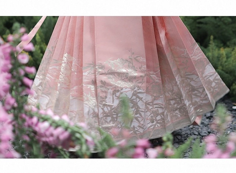 Close up of gold toned floral and bamboo jacquard hem on dusty pink Ming Dynasty Mamianqun horse face skirt