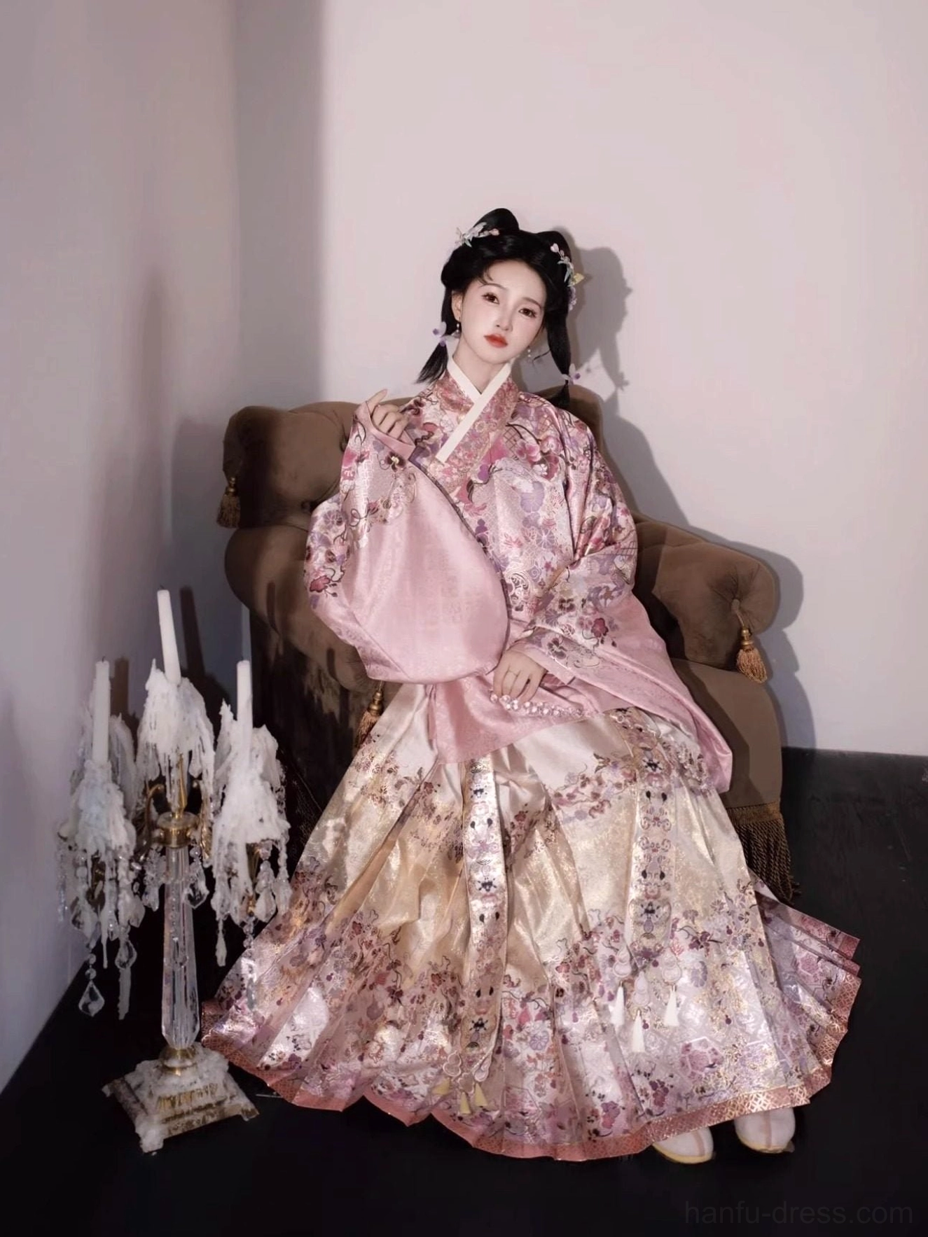 Seated front view of a dusty pink cross-collar hanfu top and full-length floral mamian skirt with smooth woven texture