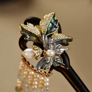 Close-up side view of ornate ebony Chinese hair stick with dark abalone shell floral design, rhinestones, pearl embellishments and tassel detail