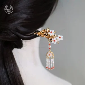 Ebony wood Chinese hair stick with gold floral ornament and red clear beaded tassel shown in a dark braided Hanfu hairstyle