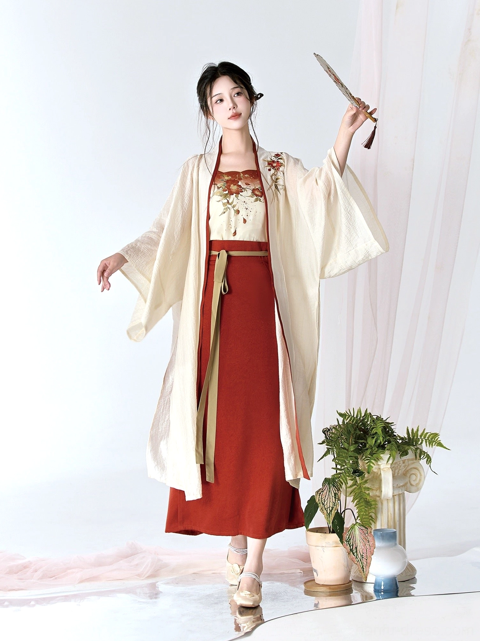 Full-body front view of elegant cream and burgundy modern Song Dynasty Hanfu with camellia details and folding hand fan