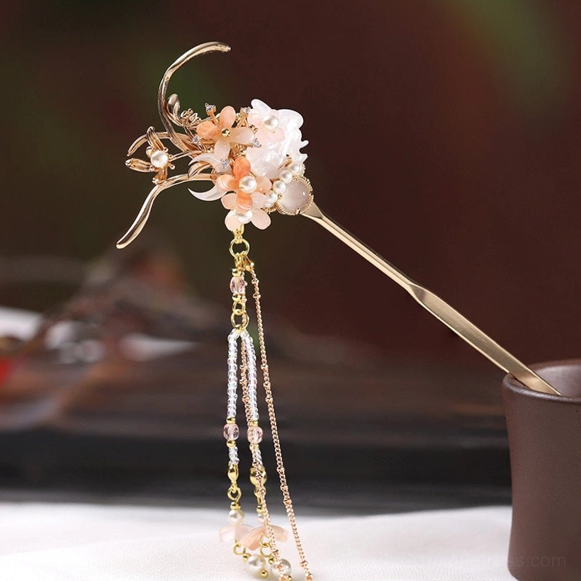 Elegant traditional Chinese hair stick with delicate gold metal details, soft pink and white flowers, pearl accents, and layered hanging tassels