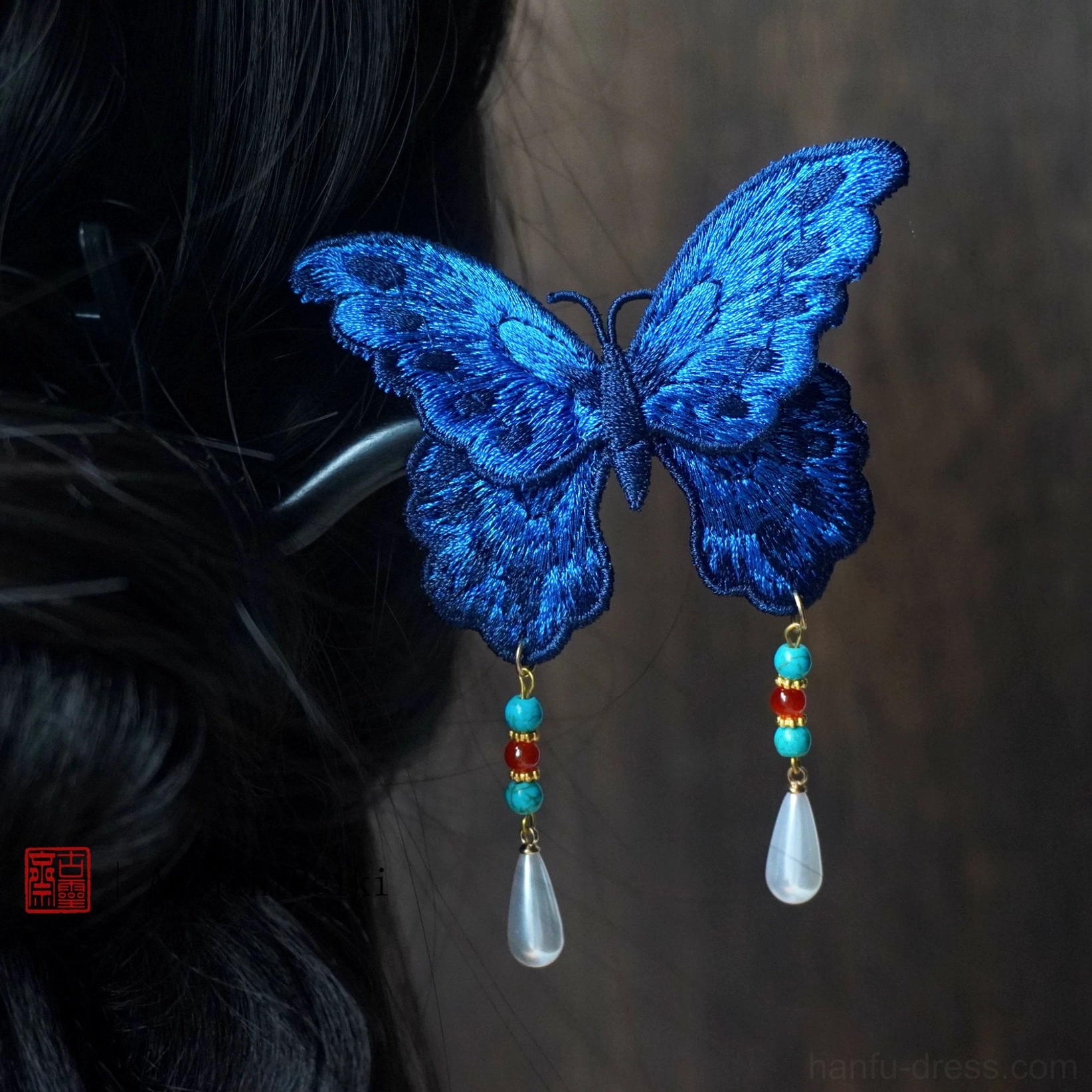 Close-up detail of embroidered blue butterfly hairpin wings colorful beads and white teardrop tassel pendants