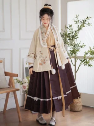 Front view of an embroidered Modern Hanfu three-piece set with beige fluffy cardigan, burgundy mamian skirt, cross-collar top, floral embroidery, lace trim, and pom-pom details
