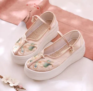 Apricot beige embroidered platform Hanfu shoes with green and golden floral embroidery, pearl ankle strap buckle, thick white rubber sole, and herringbone insole