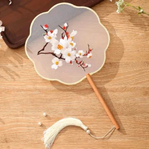 Embroidered plum blossom tuanshan traditional Chinese round hand fan with bamboo handle pearl tassel and petal-shaped sheer fan face on wooden table