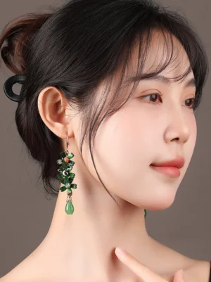 Woman wearing emerald flower teardrop Chinese earrings styled with an elegant updo in a close-up portrait