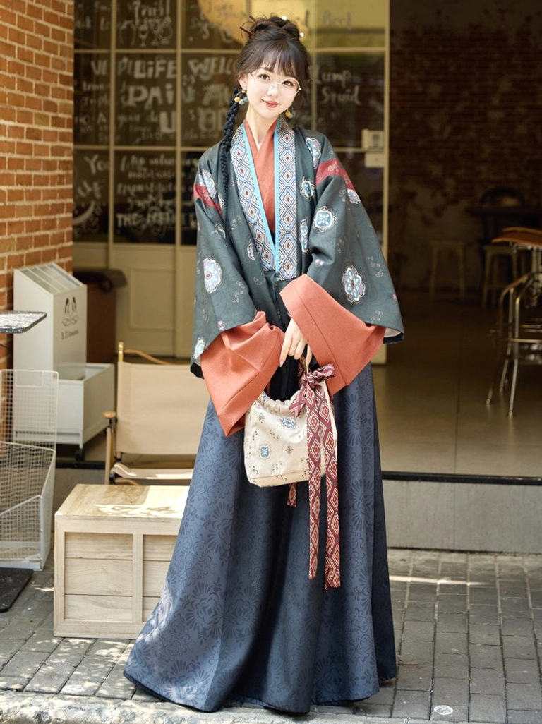 Emerald teal modern hanfu jacket and flowing navy skirt set with floral details, rust red inner top, matching waist sash, and patterned tote bag