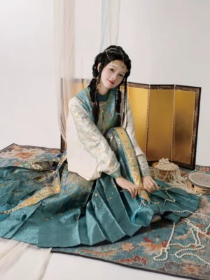 Overhead seated view of an ethnic inspired Ming Dynasty Hanfu outfit with flowing pleated mamianqun horse face skirt, woven gold motifs, pearl accessories, and elegant silhouette