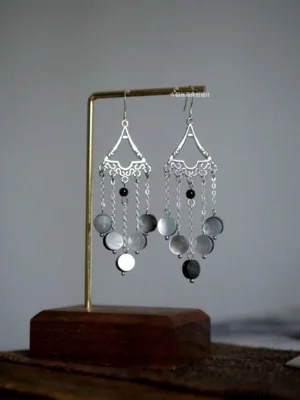 Vintage Fairy Forest Hanfu tassel earrings displayed on a brass jewelry stand, featuring silver filigree triangular tops, gray shell pendants, black beads, and dangling chain tassels