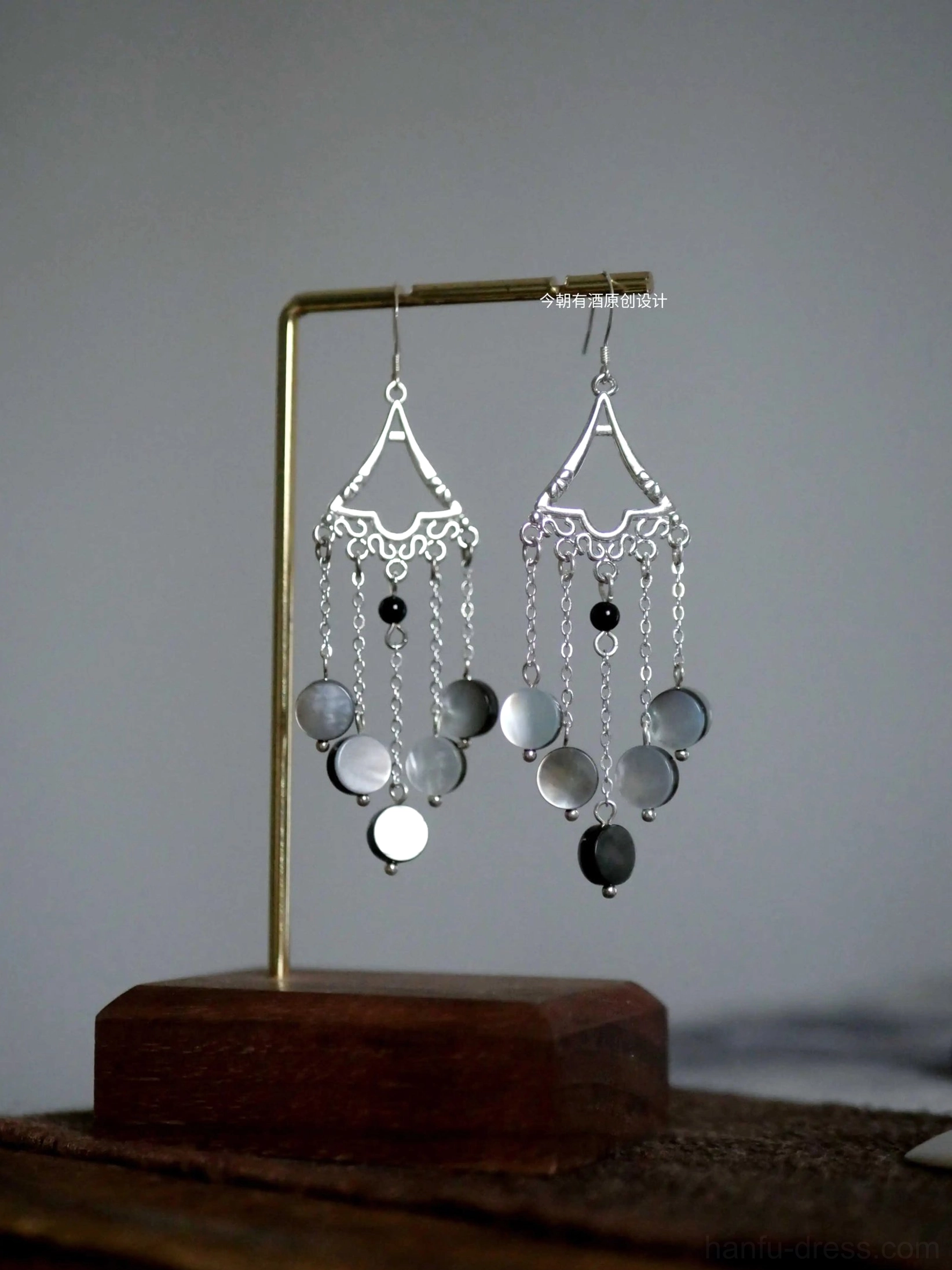 Vintage Fairy Forest Hanfu tassel earrings displayed on a brass jewelry stand, featuring silver filigree triangular tops, gray shell pendants, black beads, and dangling chain tassels