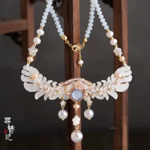 Traditional Chinese Hanfu yingluo necklace displayed on an antique wooden stand with white petal charms, gold edging, blue-gray gemstone centerpiece, pearl pendants, and elegant beaded details