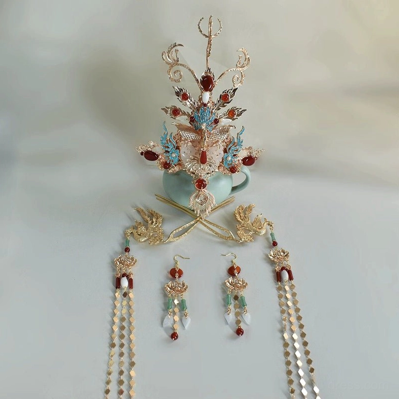 Flat lay display of a traditional Chinese hanfu hair accessory set showing the central gilded phoenix crown, hairpins, dangling earrings, long tassel pendants, red agate-style accents, and turquoise enamel-style decoration