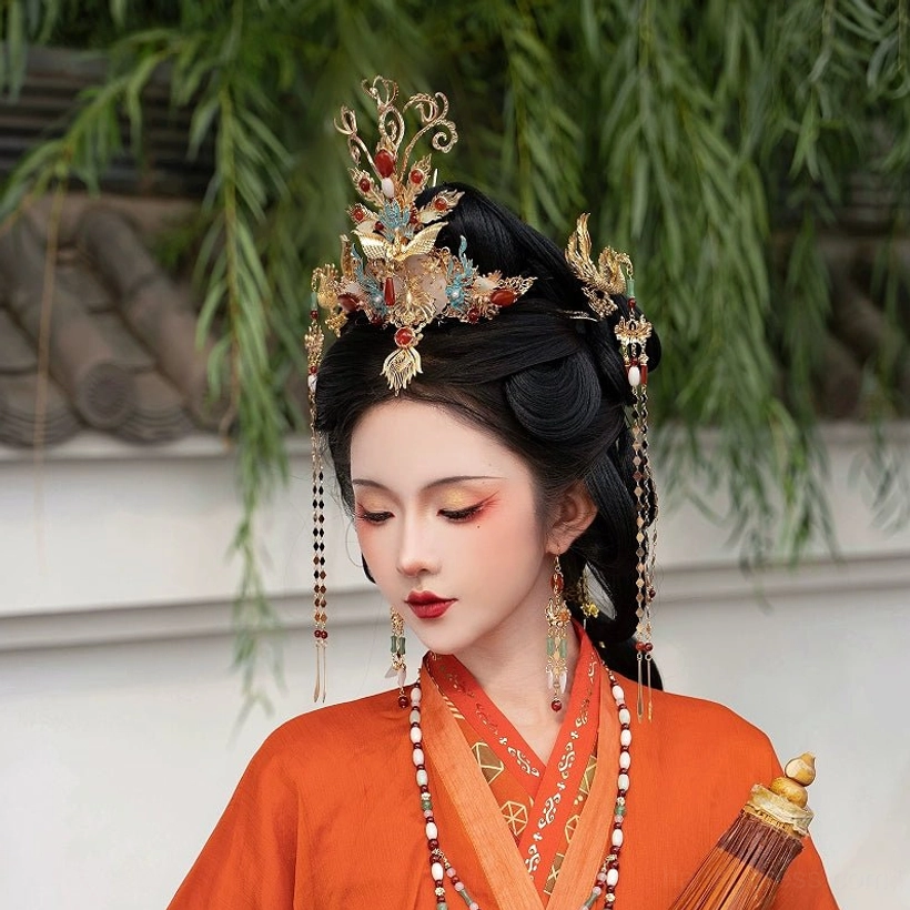 Front three-quarter view of a traditional Chinese hanfu hair accessory set with an intricately carved phoenix crown, tassel hair ornaments, and long drop earrings styled with a vintage Chinese paper umbrella