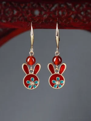 Front view of festive Chinese rabbit earrings with red enamel rabbit charms, red beads, gold-tone trim, and blue floral decoration