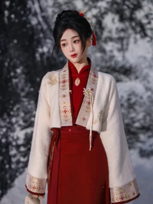 Front full-body view of an ivory festive Hanfu crop jacket styled with a traditional Chinese outfit on a model in a snowy outdoor setting