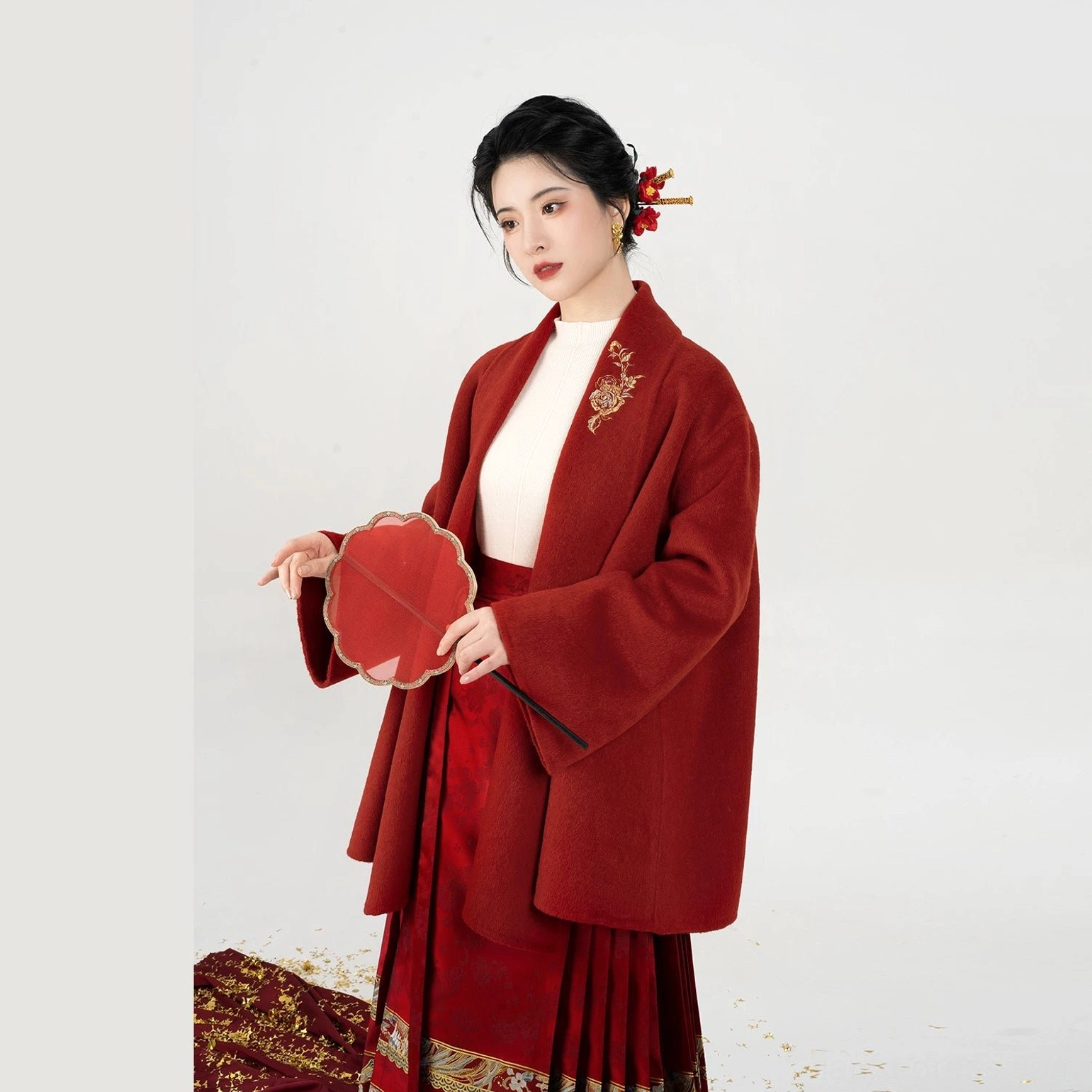 Festive modern Hanfu look with burgundy embroidered jacket, traditional Chinese hair ornaments, red round fan, and patterned skirt
