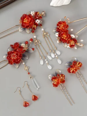 Complete festive red blossom Hanfu hair accessory set with red flower hairpins, gold tone tassels, pearl inspired beads, blue leaves and matching drop earrings on gray background