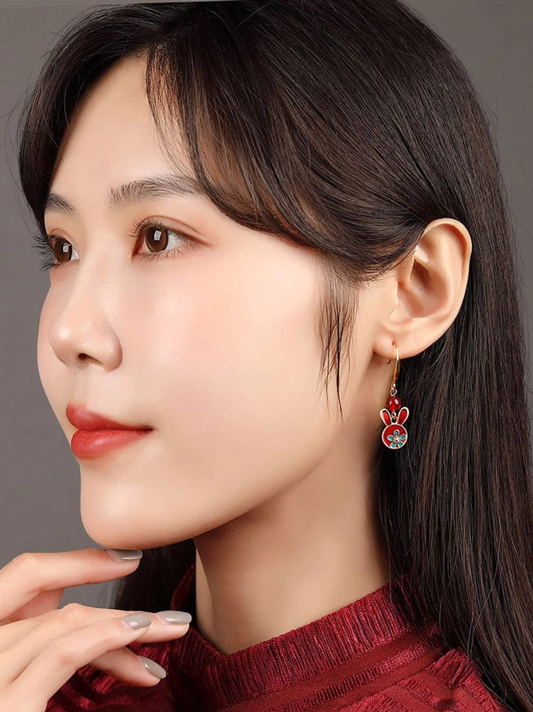 Model wearing a festive red rabbit drop earring with a dark red cheongsam top for Chinese-inspired jewelry styling