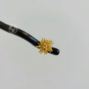 Dark wood Hanfu hair stick featuring a delicate gold fireworks decoration on a studio background