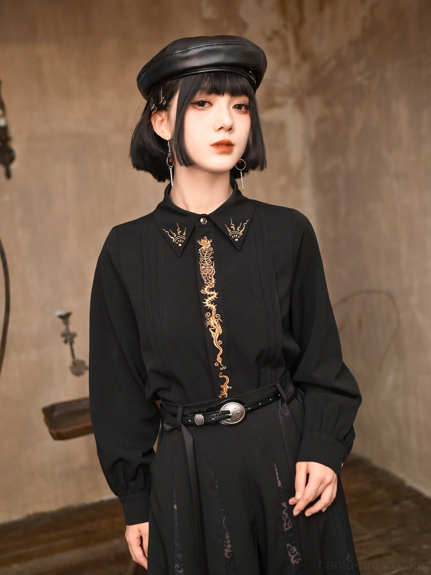 Front half-body view of black Five Poisons modern Hanfu long sleeve top with gold dragon embroidery, pleated front, lantern sleeves, and black beret styling