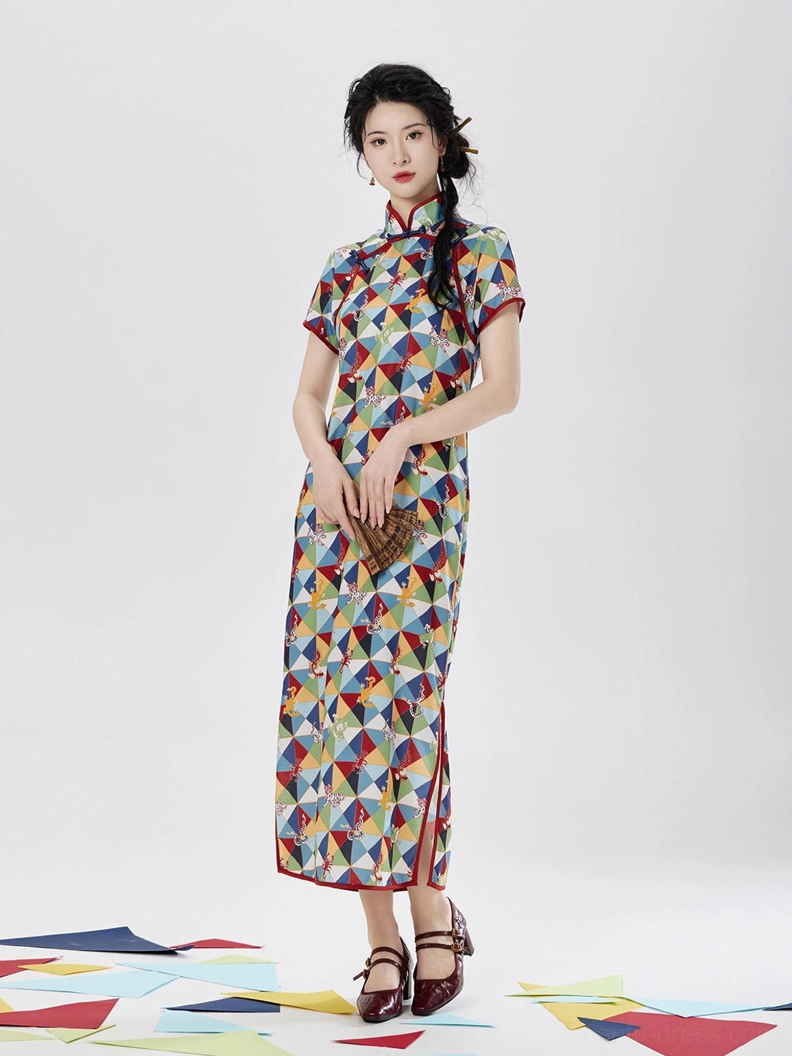 Full front view of Five Poisons short sleeve cheongsam dress with colorful geometric print, red piping, stand collar, folding fan, and side slit