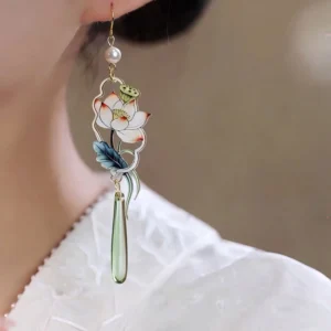 Chinese lotus Hanfu earrings worn on ear featuring pastel enamel lotus gold-tone setting and slim green glass-style drop