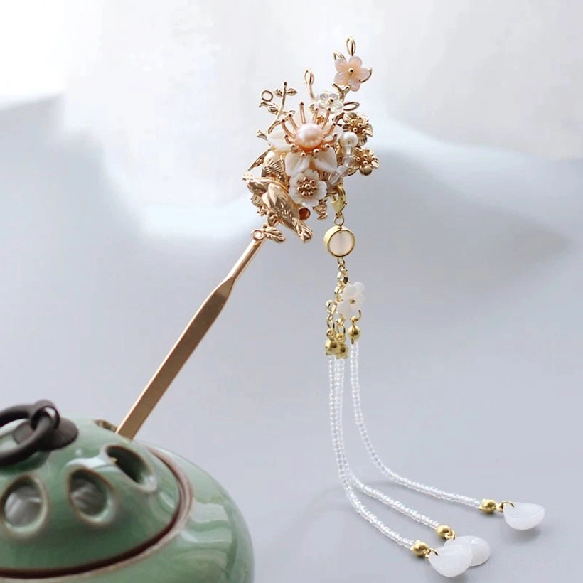 Front angled view of floral bird Chinese hair stick with gold-tone craft, pink blossoms, long beaded tassel, round pendant, and white drops