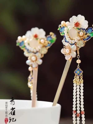 Pair of classical Chinese flower hairpins with red beaded tassels displayed in a white ceramic cup for Hanfu hairstyle styling