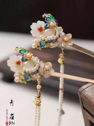 Gold-tone Chinese tassel hair sticks with enamel flowers pearl-like beads jade-style petals and long beaded pendants displayed on a wooden table